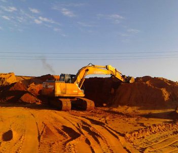 Excavator moving a sand stockpile at a construction site