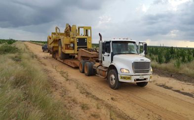 Truck transporting heavy industrial equipment along a dirt road