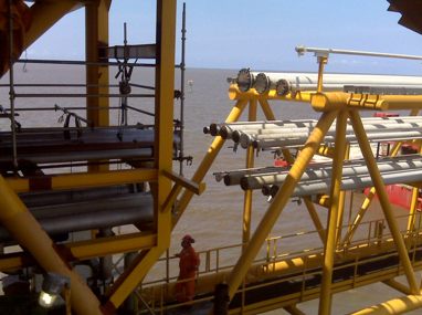 Yellow steel pipe spools staged on an offshore platform deck
